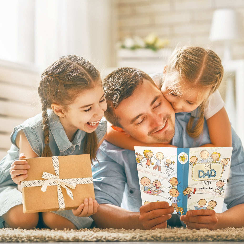 Two young girls, ages 5 and 6 reading a personalized best dad ever book that was written by them and smiling, there's a gift in the 6 year old's hands