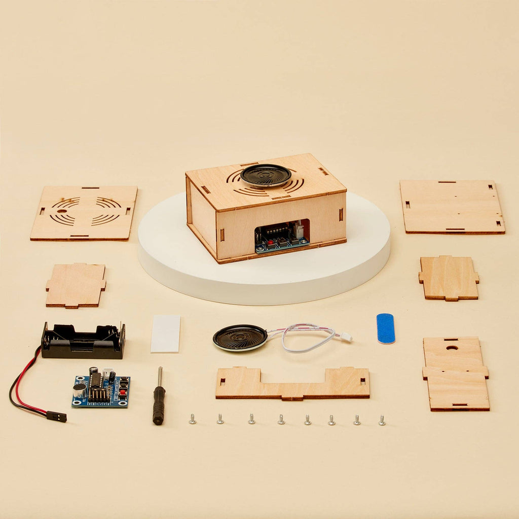 Voice Recorder DIY Kit, STEM Toy for children. All parts showing how kids can record themselves on this after being bult on a yellow backdrop and tools
