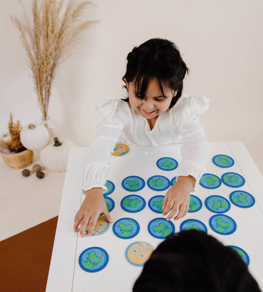 dark hair child playing the kids of the world memory match educational game on white table