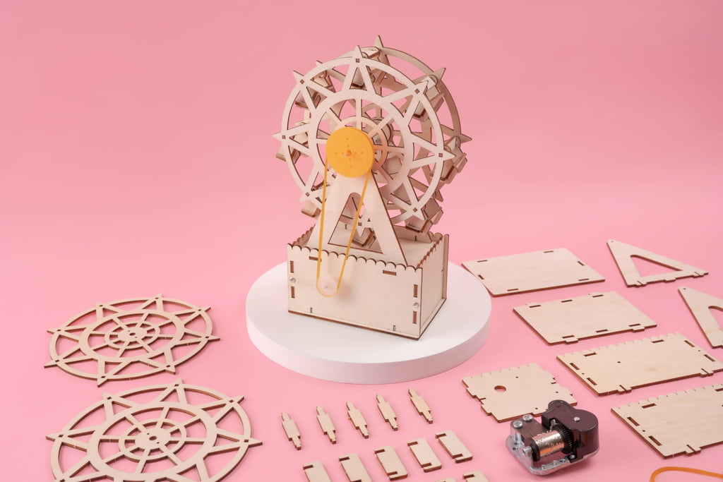 Music Box Ferris Wheel DIY Kit, Fun STEM Toy for Kids showing all pieces on a pink backdrop, build it and it will play music